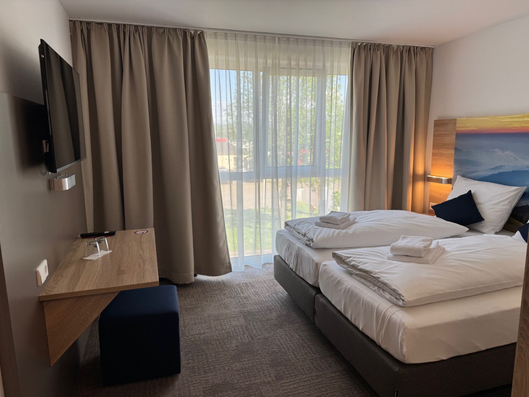 Modernes Businesszimmer mit Doppelbett, Schreibtisch und TV