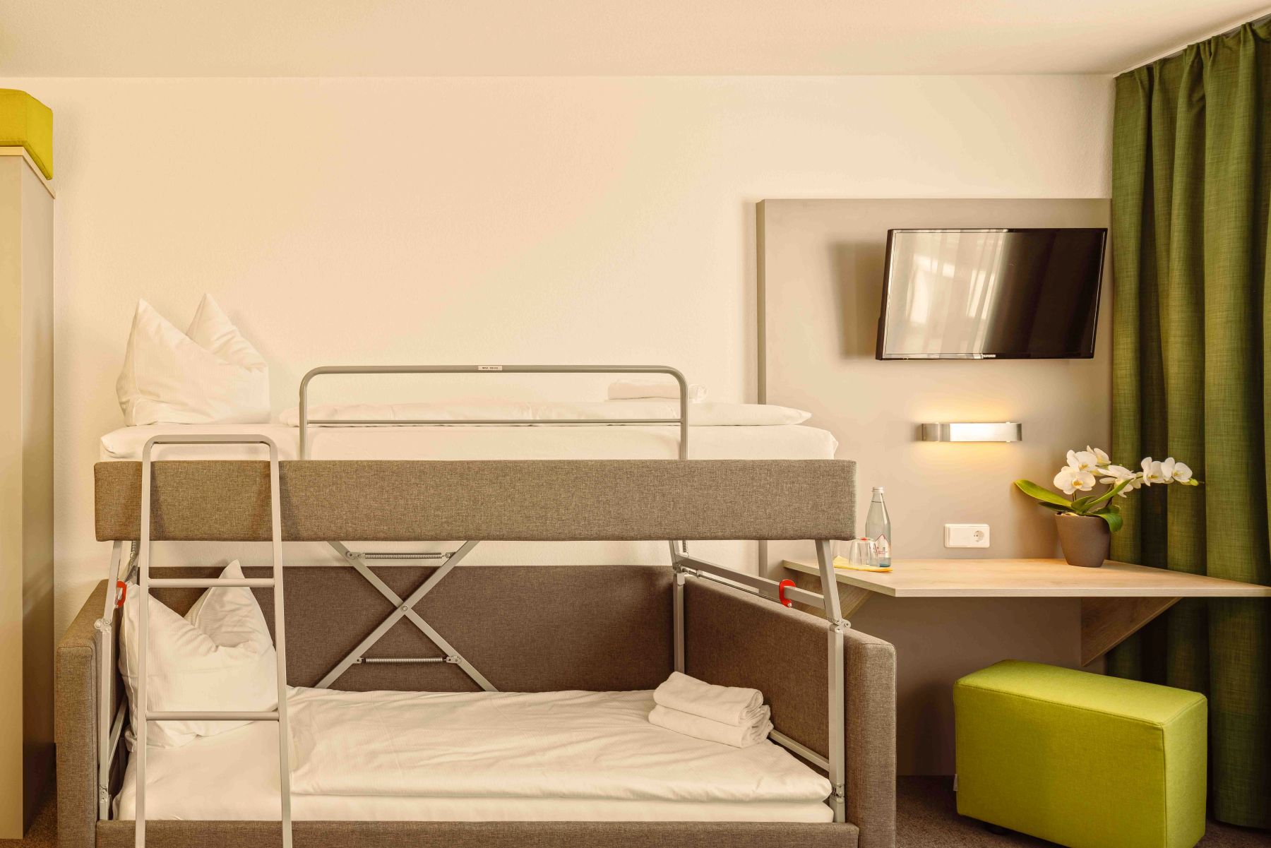 Mehrbettzimmer mit Etagenbett und Sitzbereich im modernen Hotelzimmer