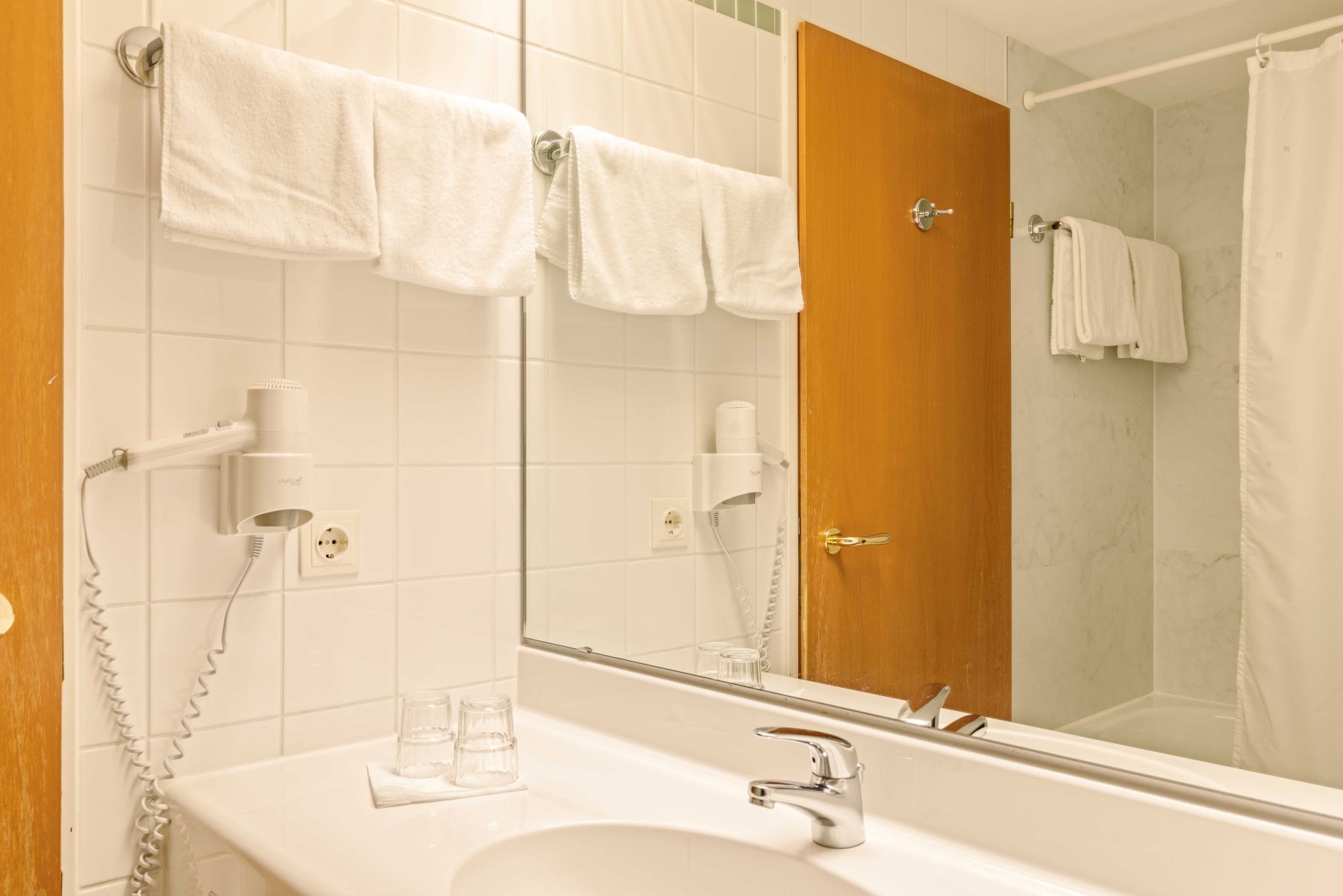 Badezimmer mit Waschbecken, Spiegel und Handtüchern im Mehrbettzimmer